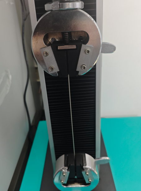 Small-diameter stainless steel specimen held directly in tensile test grips